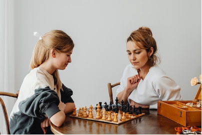 Mother and daughter sitting at a table and playing chess